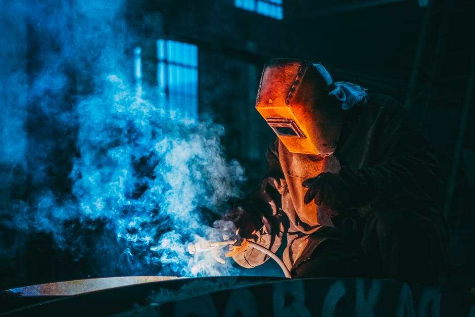 welder with mask on, smoke rising