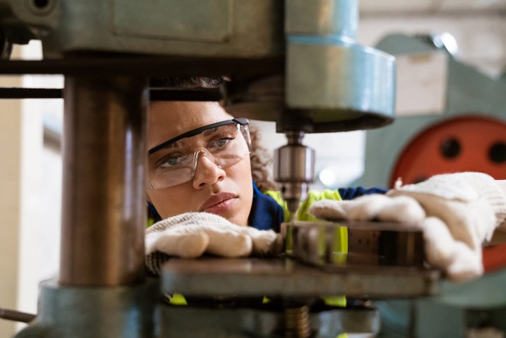 Female apprentice using yoke machine in factory