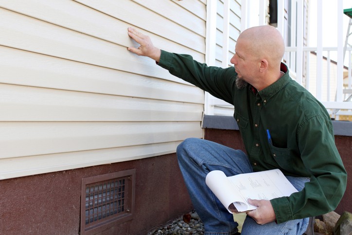 Home inspector checking out aluminum siding on house.