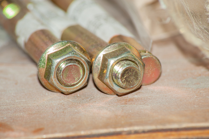 Hexagonal nut and washer on metal galvanized anchor bolt end on black background.