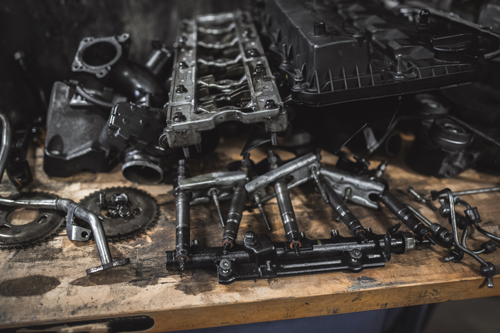 Close-up of a disassembled engine, showcasing various parts like valves, injectors, and other components on a wooden surface. Ideal for illustrating automotive repair or mechanics.