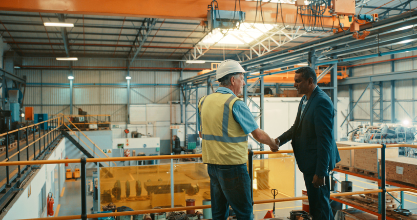 Business people at an industrial workshop shaking hands at a factory. Successful business man congratulating contractor for excellent work on maintenance, development and management.